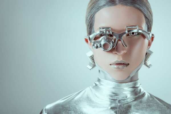 close-up view of silver robot looking at camera isolated on grey, future technology concept 