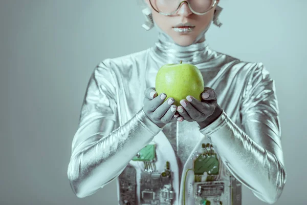 cropped shot of cyborg holding green apple isolated on grey, future technology concept