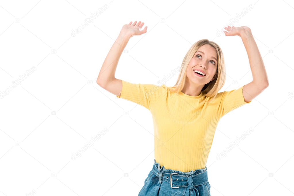 cheerful young woman raising hands and looking up isolated on white 