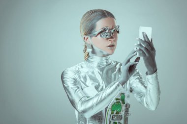 silver cyborg using smartphone isolated on grey, future technology concept clipart