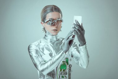 Genç kadın robot izole gri, geleceğin teknoloji kavramı üzerinde smartphone kullanarak