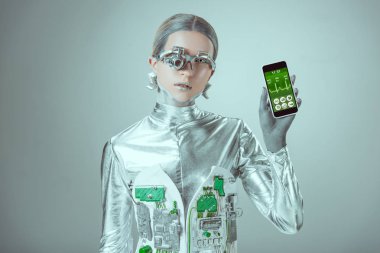 robot Smartphone sağlık uygulama ile tutarak ve izole gri, geleceğin teknoloji kavramı üzerinde kamera bakıyor   