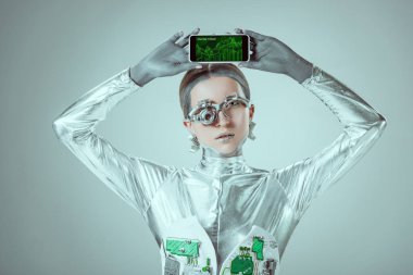 robot Smartphone online ticaret uygulaması ile tutarak ve izole gri, geleceğin teknoloji kavramı üzerinde kamera bakıyor 