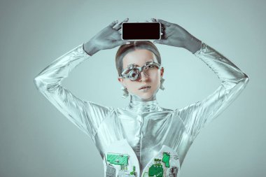 Gümüş robot ile izole gri, geleceğin teknoloji kavramı üzerinde başının üstünde boş perde Smartphone holding