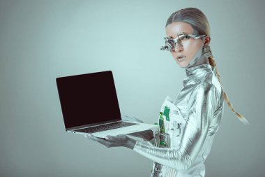 Gümüş robot izole gri, geleceğin teknoloji kavramı üzerinde boş ekranlı dizüstü holding