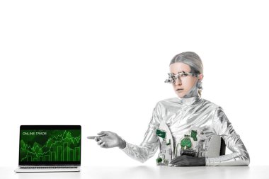 masada oturan ve izole beyaz, geleceğin teknoloji kavramı üzerinde online ticaret cihazı ile dizüstü bilgisayarda işaret gümüş robot