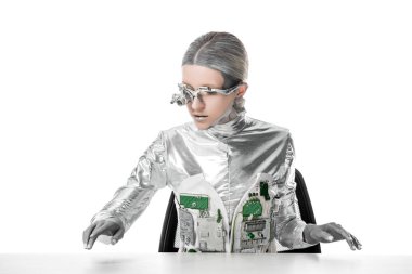 masada oturan ve izole beyaz, geleceğin teknoloji kavramı üzerinde masa üzerinde bir şey dokunmak gümüş robot