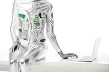 masada oturan ve izole beyaz, geleceğin teknoloji kavramı üzerinde dizüstü kullanarak robot kırpılmış görüntü