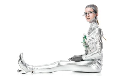 Beyaz, geleceğin teknoloji kavramı üzerinde oturan ve kameraya bakarak gümüş robot yan görünüm izole