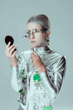 aynaya bakarak ve izole gri, geleceğin teknoloji kavramı üzerinde ruj tutan gümüş robot