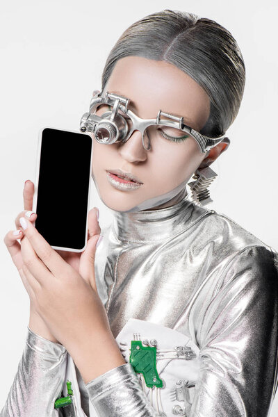 silver robot holding smartphone with blank screen isolated on white, future technology concept