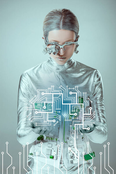 futuristic silver cyborg looking at circuit board isolated on grey, future technology concept 