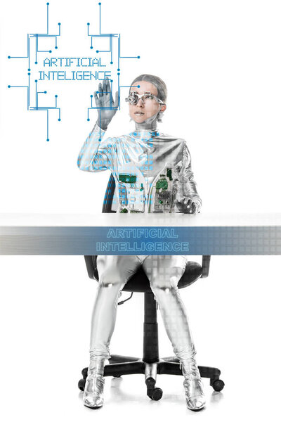 cyborg sitting at table and touching "artificial intelligence" lettering in digital data isolated on white, future technology concept 