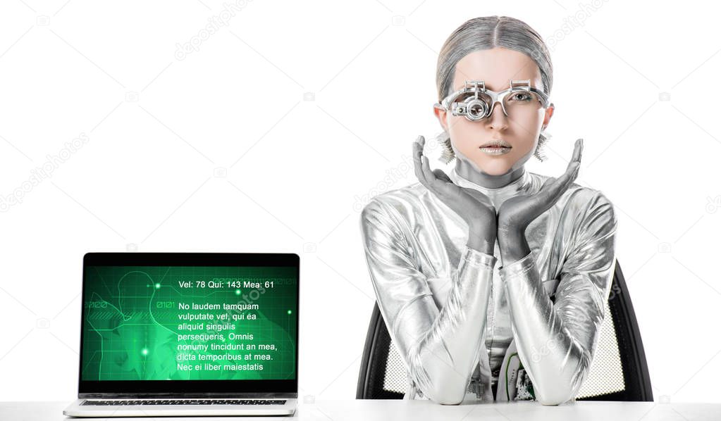 silver robot sitting at table near laptop with medical appliance isolated on white, future technology concept