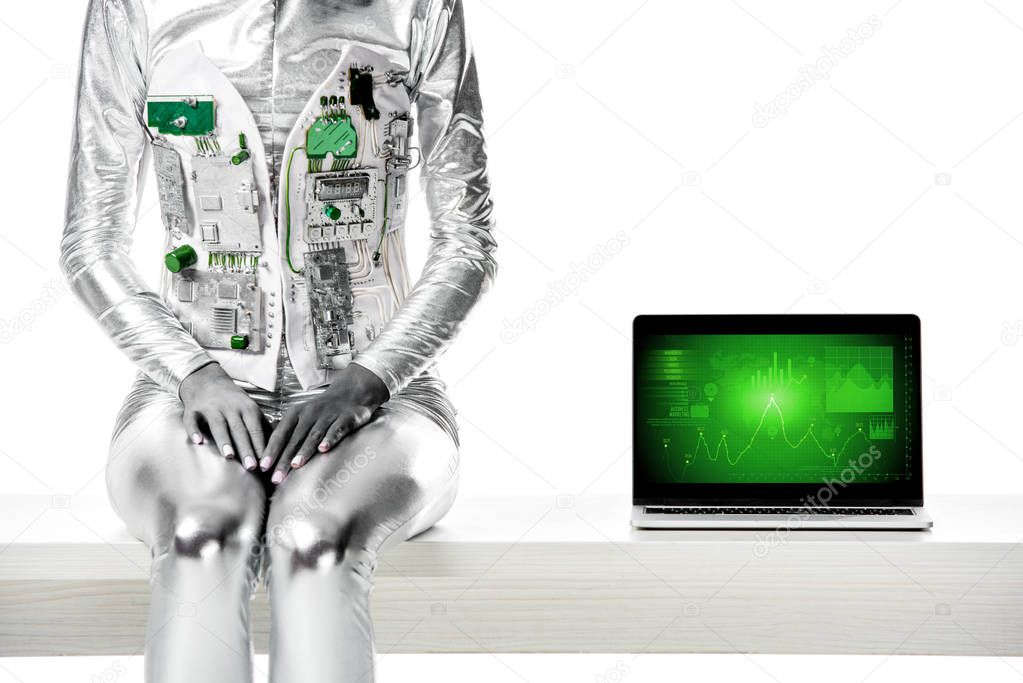 cropped image of robot sitting on table near laptop with business appliance isolated on white, future technology concept