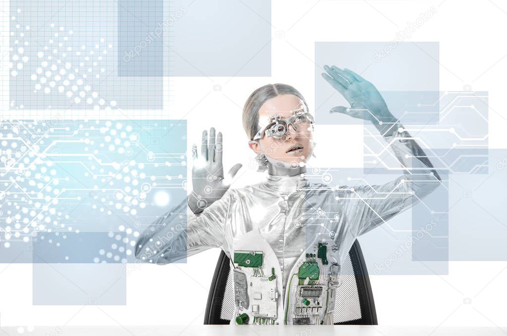 cyborg with eye prosthesis sitting at table and touching digital data isolated on white, future technology concept 