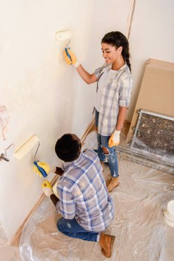 high angle view of happy young couple painting wall during renovation of home clipart