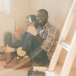 Happy young couple relaxing on floor with beer while making renovation of home