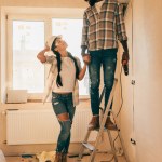 幸せな若いカップルは一緒に家の改築を作るステップはしご