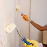 Imagem cortada de parede de pintura de casal por rolos de pintura em nova casa