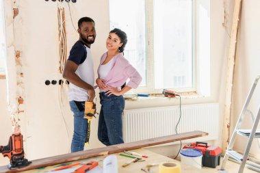 selective focus of happy african american couple posing during renovation of new home clipart