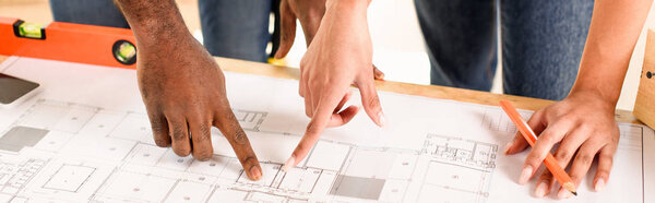 cropped image of couple pointing by finger at blueprint