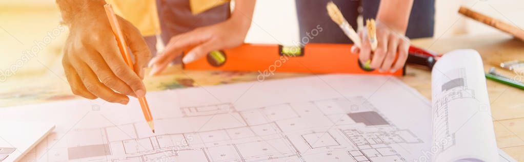 cropped image of couple making notes in blueprint for renovation 