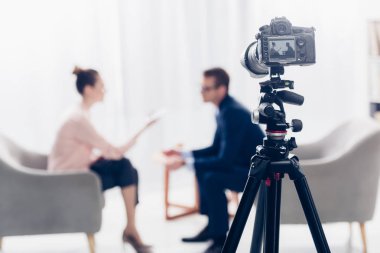 gazeteci ofiste, fotoğraf makinesi tripod üzerinde ön plan üzerinde röportaj veren işadamı