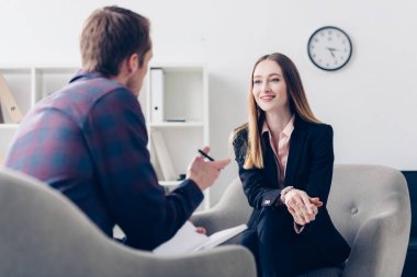 happy businesswoman in suit giving interview to journalist in office clipart