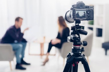 işkadını ofis, fotoğraf makinesi tripod üzerinde ön plan üzerinde gazeteci röportaj veren takım elbiseli