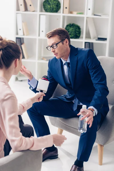 Knappe Zakenman Holding Fles Water Journalist Interview Geven Met Microfoon — Gratis stockfoto