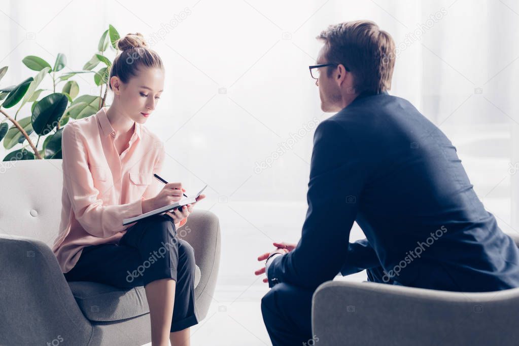 handsome businessman giving interview to attractive young journalist in office