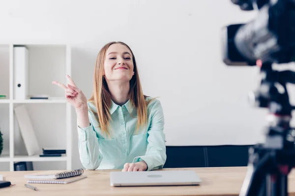 微笑着吸引女性视频博主录制 Vlog 并显示两个手指在办公室 — 图库照片