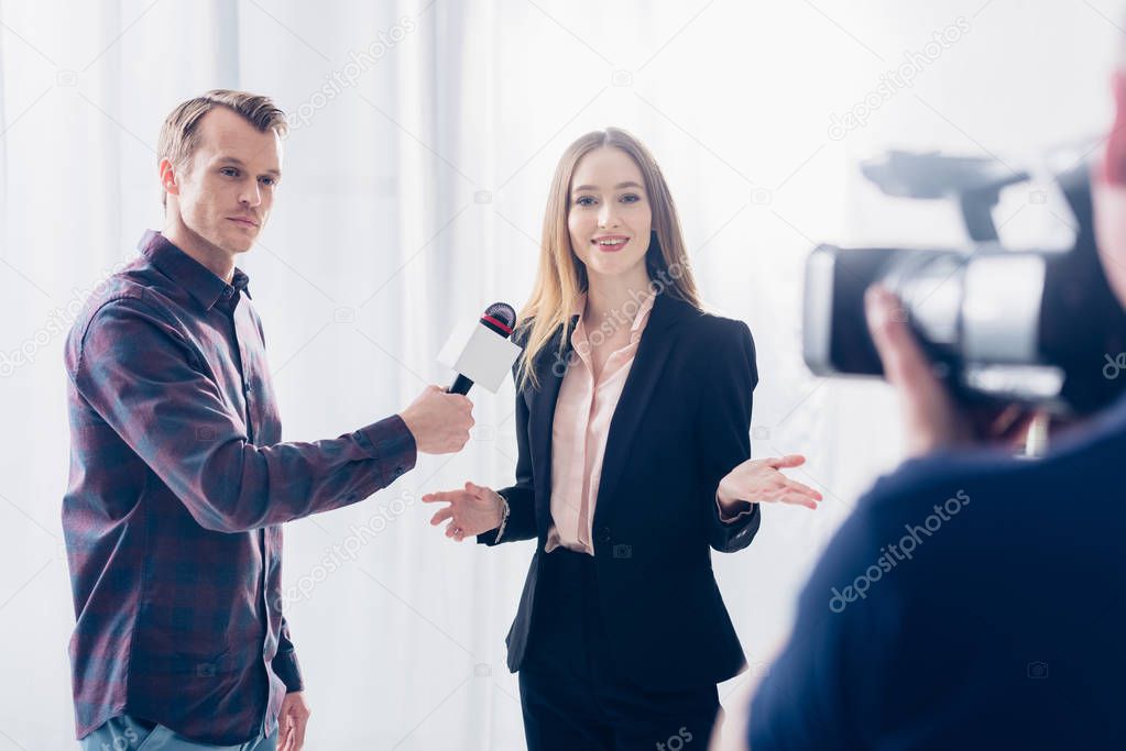beautiful businesswoman in suit giving interview to journalist and gesturing in office