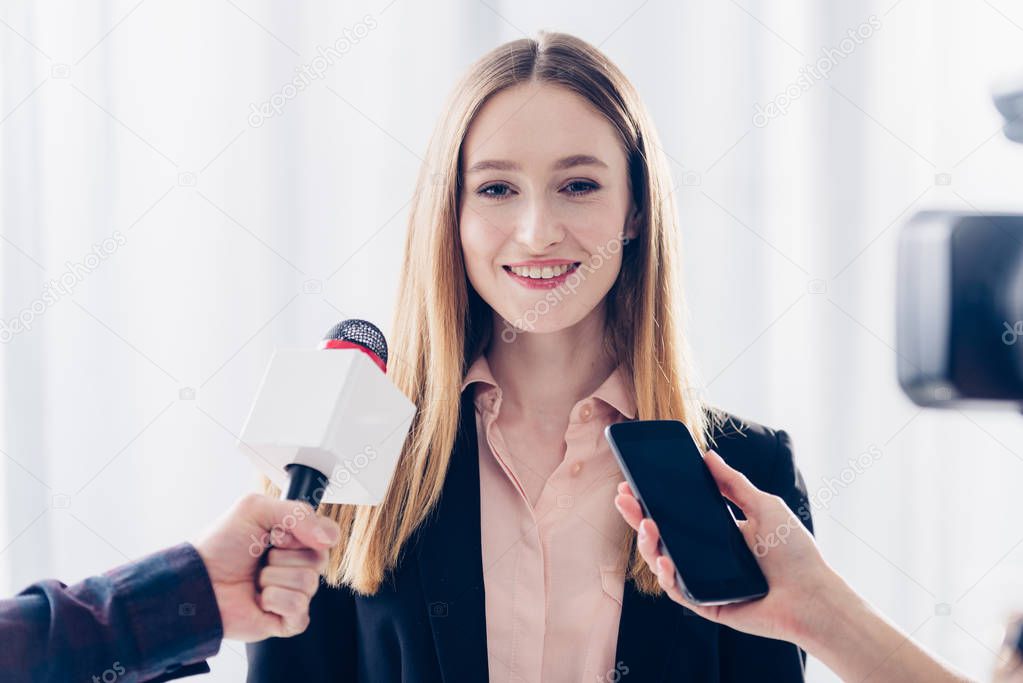 smiling attractive businesswoman giving interview to journalists in office