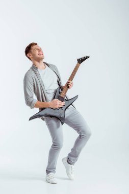 adam gri giyim gri arka plan üzerinde elektro gitar çalmak heyecanlı