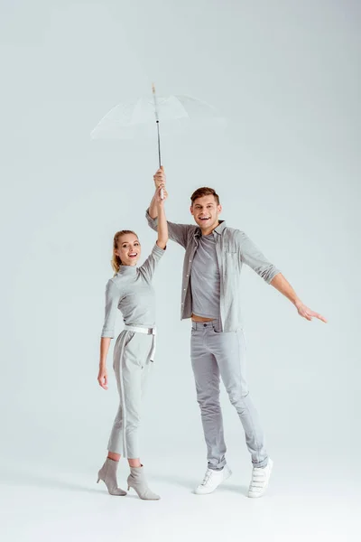 Aufgeregtes Paar Steht Auf Zehenspitzen Und Posiert Mit Transparentem Regenschirm — Stockfoto