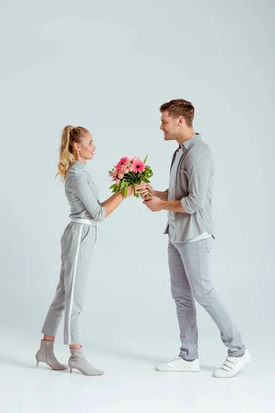 Lächelnder Mann Gibt Frau Rosa Blumenstrauß Auf Grauem Hintergrund — Stockfoto