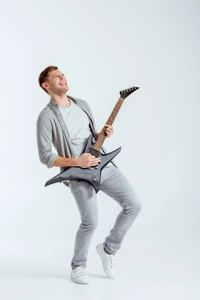 灰色の背景で電気ギターを弾く灰色の服の男を興奮 — ストック写真