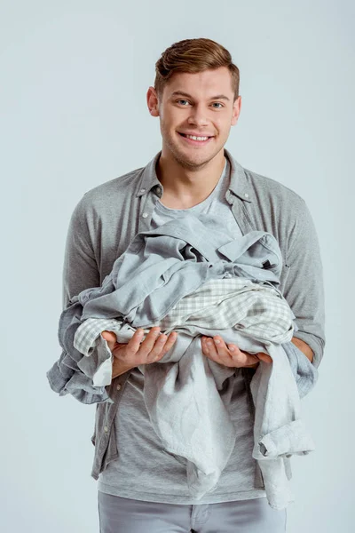 Smiling Handsome Man Looking Camera Holding Pile Grey Clothes Isolated — Stock Photo, Image