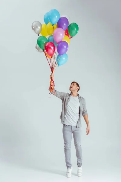 Bonito Homem Ponta Dos Pés Segurando Pacote Balões Coloridos Fundo — Fotografia de Stock