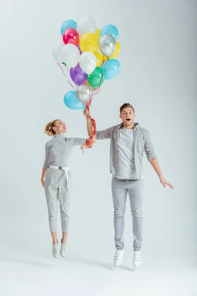 Pareja Emocionada Saltando Con Paquete Globos Colores Sobre Fondo Gris — Foto de Stock