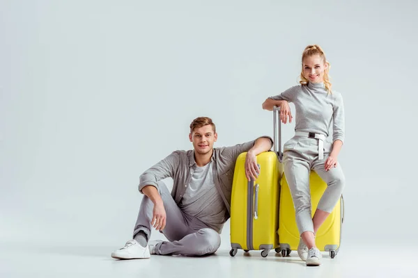 Couple Sitting Yellow Suitcases Looking Camera Grey Background Travel Concept — Stock Photo, Image