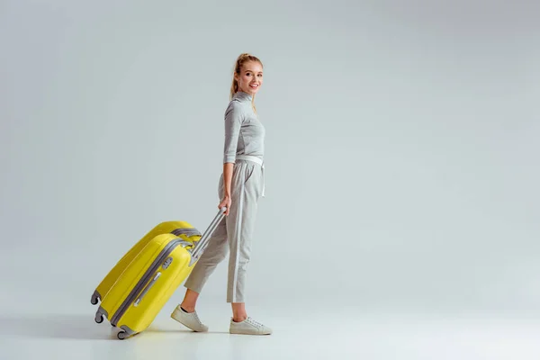 Woman Carrying Yellow Suitcases Looking Camera Grey Background Travel Concept — Stock Photo, Image