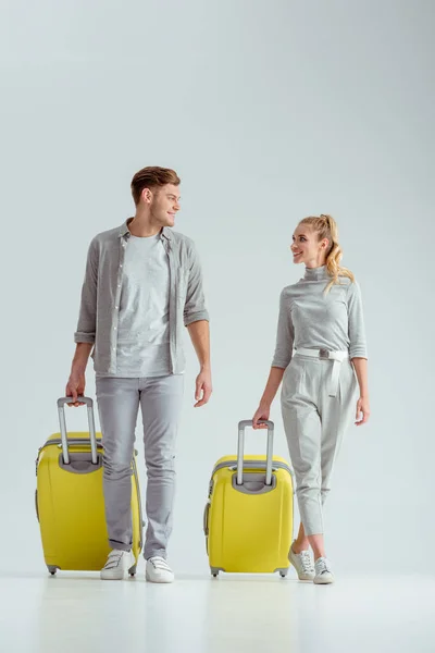 Happy Couple Carrying Yellow Suitcases Looking Each Other Grey Background — Stock Photo, Image