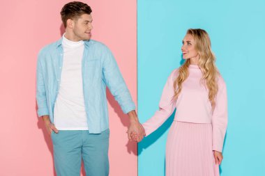 Elele ve pembe ve mavi arka plan üzerinde birbirine bakarak mutlu çift