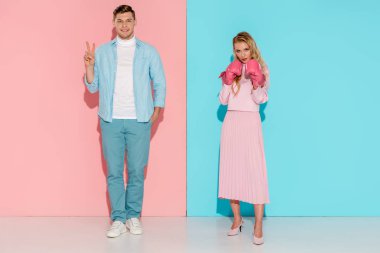 adam barış işareti kadın boks eldivenleri pembe ve mavi arka plan üzerinde poz sırasında gösterilen