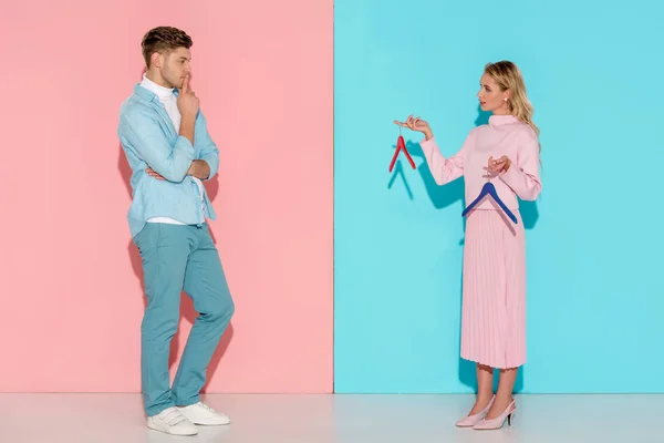 Thoughtful Man Looking Woman Choosing Empty Clothes Hangers Pink Blue — Stock Photo, Image