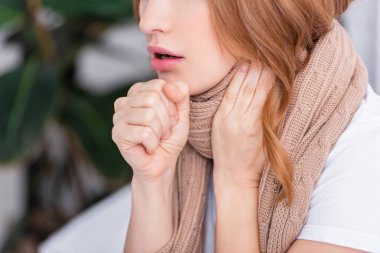 cropped image of sick woman coughing and touching neck at home clipart