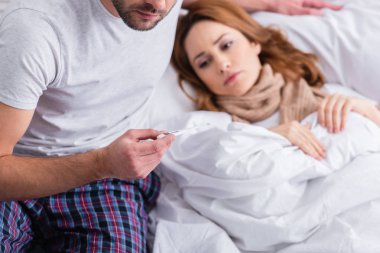hasta kadını sıcaklığını kontrol ve termometre yatak odasında tutan koca resim kırpılmış